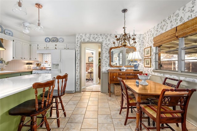 dining space featuring baseboards, ceiling fan with notable chandelier, and wallpapered walls