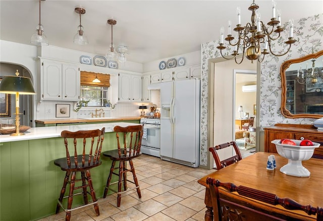 kitchen with pendant lighting, light countertops, white cabinets, an inviting chandelier, and white appliances
