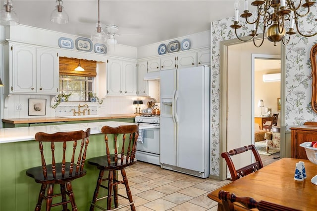 kitchen with white appliances, white cabinets, a chandelier, and light countertops