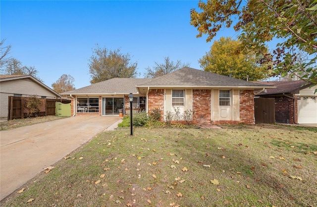 ranch-style home featuring a front yard, a gate, brick siding, fence, and concrete driveway