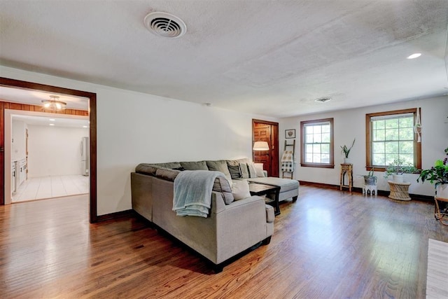 living room featuring visible vents, light wood-style floors, and baseboards