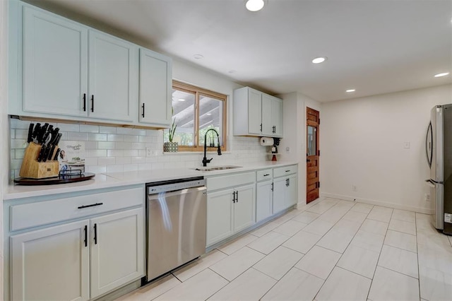 kitchen with light countertops, stainless steel appliances, decorative backsplash, and a sink