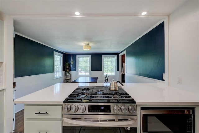 kitchen with stainless steel range with gas stovetop, crown molding, white cabinets, and light countertops