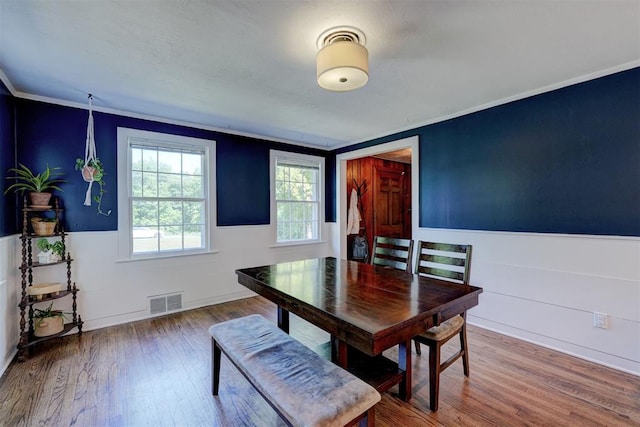 dining room with visible vents, wainscoting, crown molding, and wood finished floors