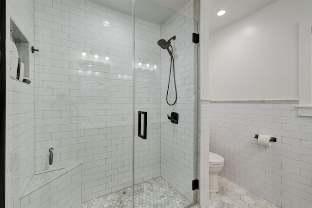 full bathroom featuring tile walls, a shower stall, a wainscoted wall, toilet, and recessed lighting