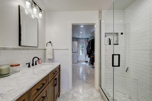 full bathroom with wainscoting, tile patterned flooring, vanity, tile walls, and a stall shower