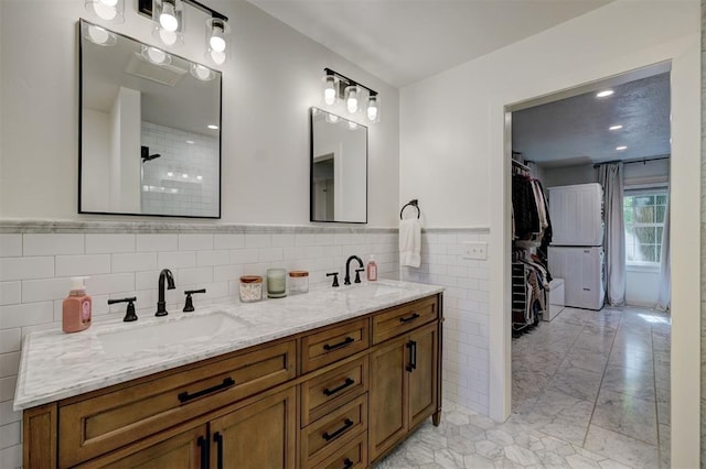 full bathroom featuring double vanity, a sink, marble finish floor, and tile walls