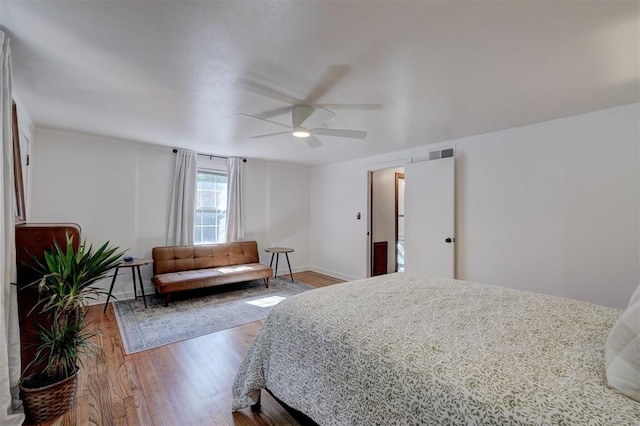 bedroom with baseboards, ceiling fan, wood-type flooring, and visible vents