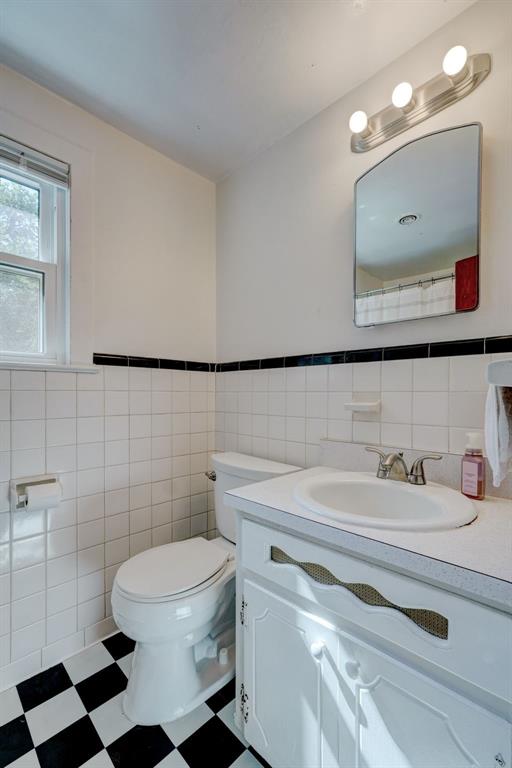 bathroom with tile walls, wainscoting, vanity, tile patterned floors, and toilet