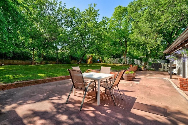 view of patio featuring a playground, outdoor dining space, and a fenced backyard
