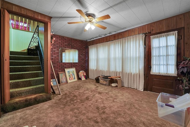 rec room with plenty of natural light, wood walls, carpet, and ceiling fan