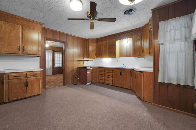 kitchen featuring light countertops, ceiling fan, and brown cabinets