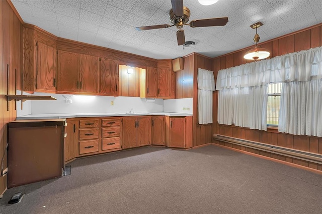 kitchen with carpet floors, brown cabinetry, ceiling fan, and light countertops
