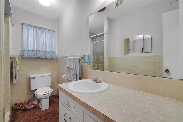 bathroom featuring toilet, a shower stall, a wainscoted wall, and vanity
