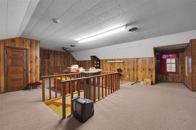 additional living space featuring wooden walls, carpet, a ceiling fan, and lofted ceiling