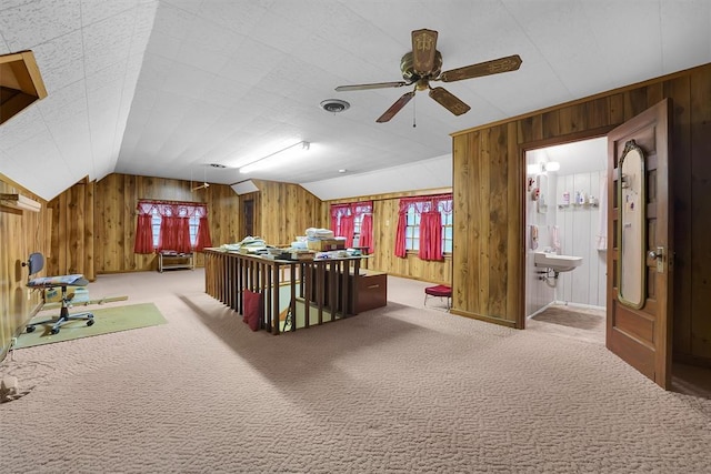 carpeted office space with wooden walls, a ceiling fan, and vaulted ceiling