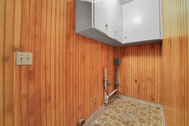 washroom featuring wood walls and cabinet space