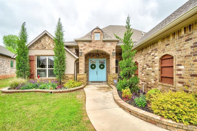 doorway to property with a lawn, roof with shingles, and brick siding