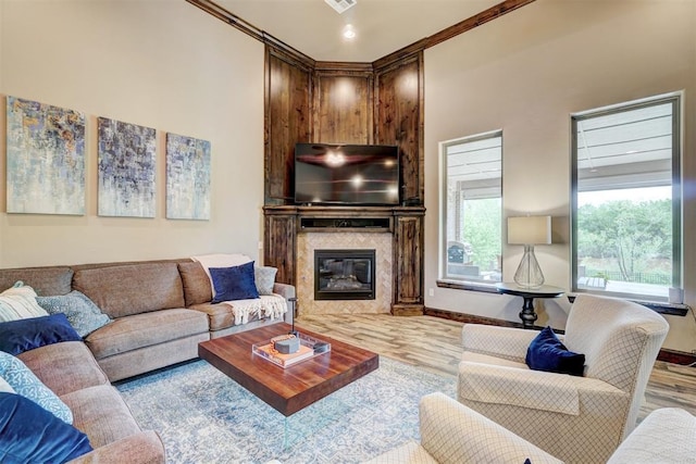 living room with a high end fireplace, baseboards, ornamental molding, and wood finished floors