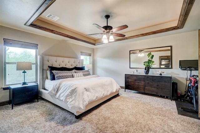 carpeted bedroom featuring visible vents, a raised ceiling, ceiling fan, and multiple windows