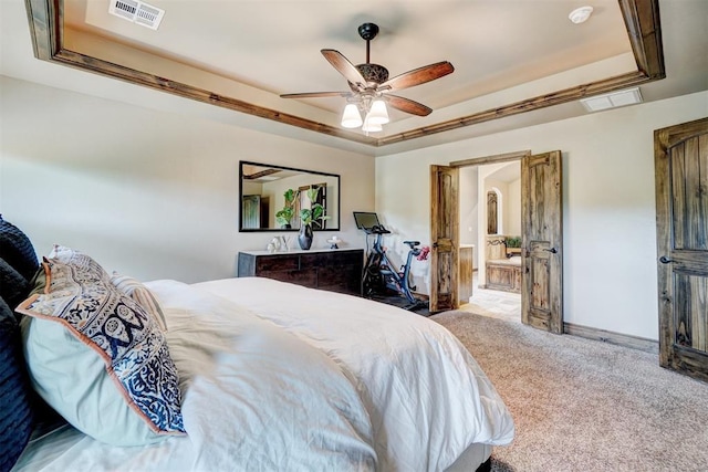carpeted bedroom featuring a ceiling fan, a tray ceiling, and visible vents