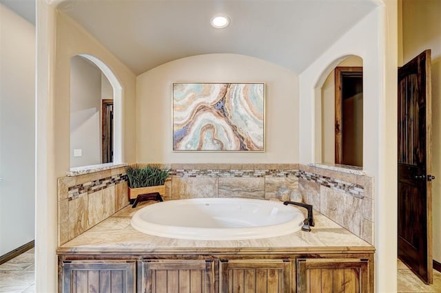 bathroom with recessed lighting, lofted ceiling, and a bath