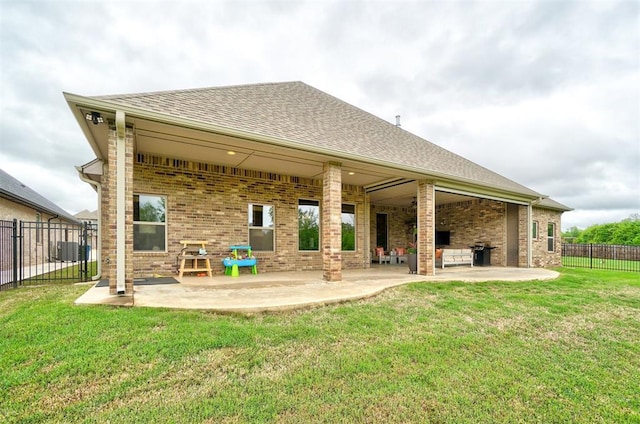 rear view of house featuring fence, roof with shingles, brick siding, a patio area, and a lawn