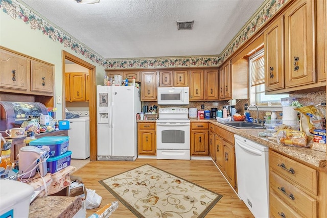 kitchen with a sink, white appliances, light countertops, a textured ceiling, and visible vents