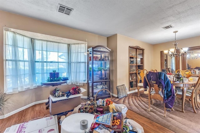 living area with a textured ceiling, a chandelier, and visible vents