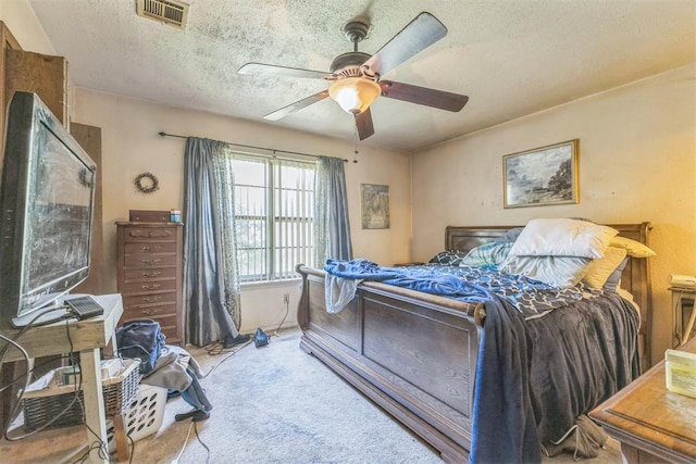carpeted bedroom featuring a ceiling fan, a textured ceiling, and visible vents