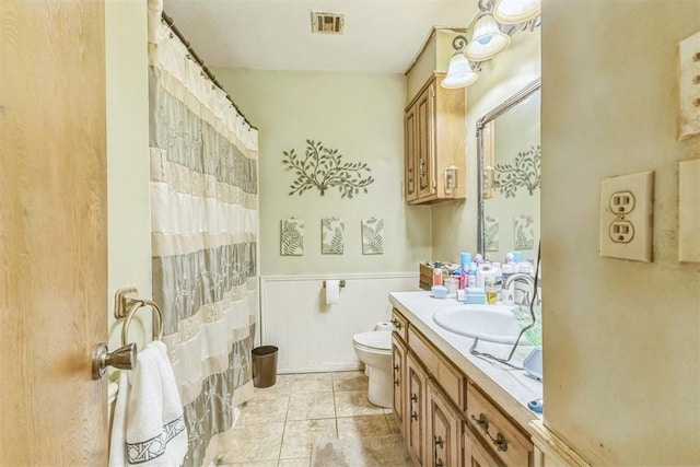 bathroom with visible vents, vanity, toilet, a shower with shower curtain, and a wainscoted wall