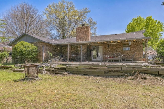 back of property featuring a shingled roof, brick siding, a wooden deck, a chimney, and a yard