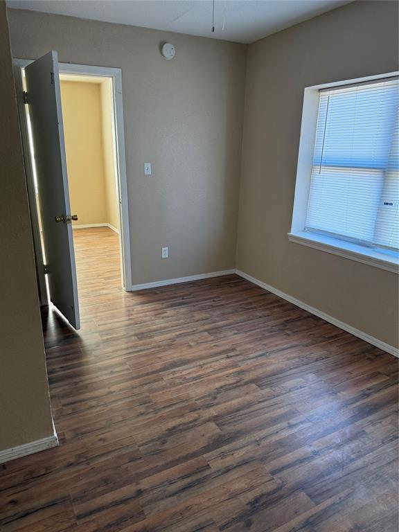 spare room with dark wood-style flooring and baseboards
