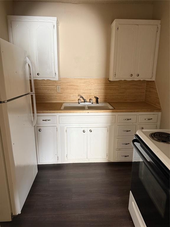 kitchen featuring dark wood finished floors, a sink, freestanding refrigerator, electric stove, and white cabinetry