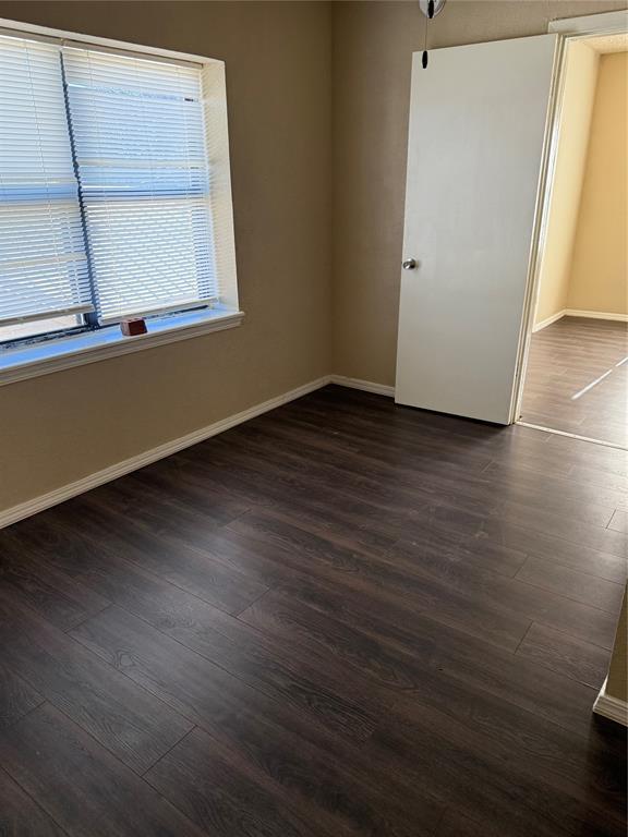 empty room featuring baseboards and dark wood finished floors