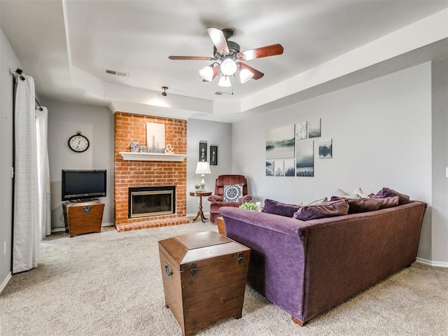 living room featuring visible vents, a brick fireplace, light carpet, a raised ceiling, and a ceiling fan