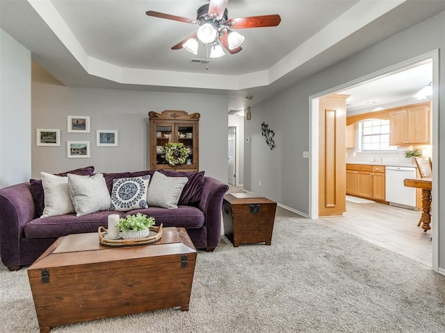 living room with light colored carpet, a ceiling fan, baseboards, and visible vents