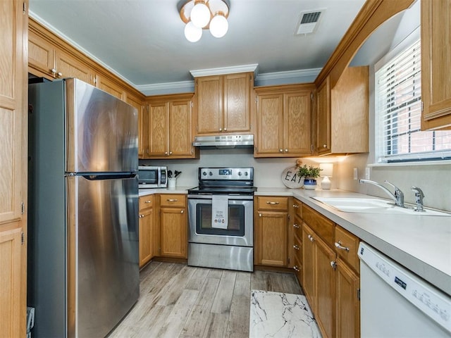 kitchen featuring visible vents, light countertops, under cabinet range hood, light wood-style flooring, and stainless steel appliances