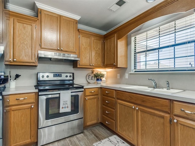 kitchen with light countertops, stainless steel electric range oven, under cabinet range hood, and a sink