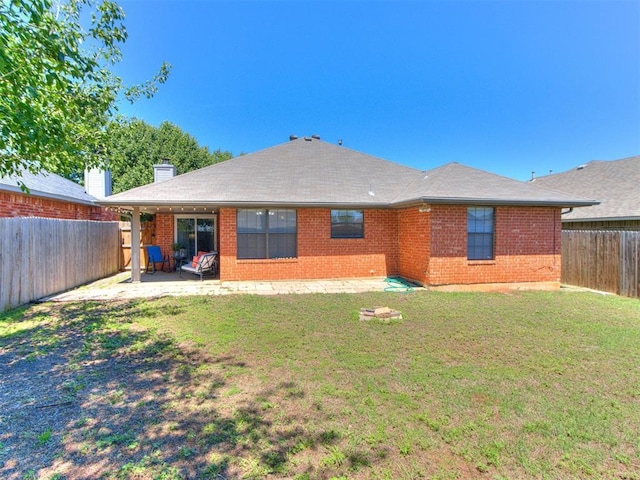 back of property featuring brick siding, a fenced backyard, a chimney, a lawn, and a patio