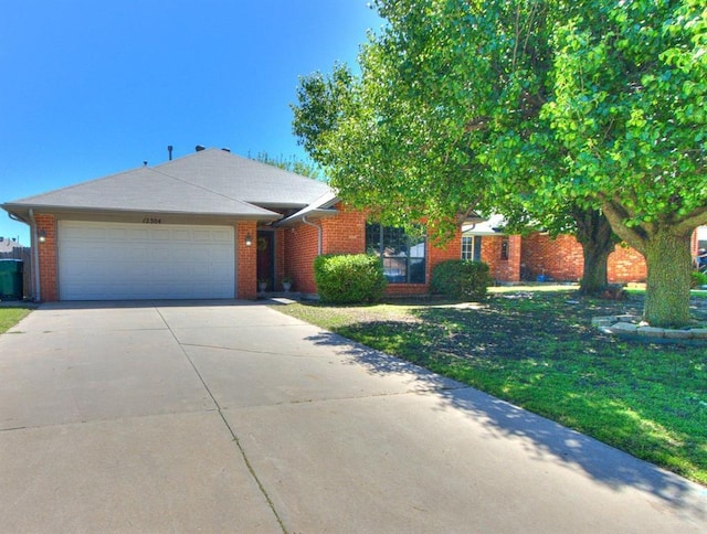 view of front of home with an attached garage, a front lawn, driveway, and brick siding