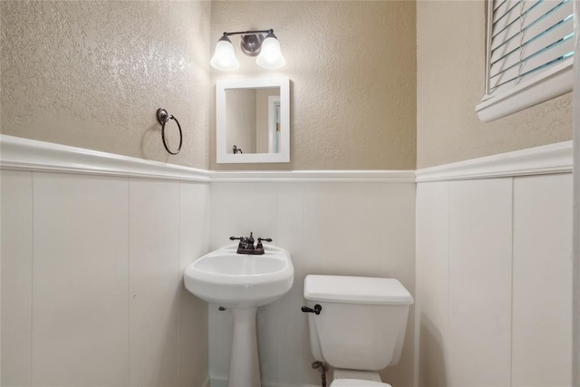 2417 NW 55th Ter, Oklahoma City, OK 73112 - bathroom featuring a decorative wall, toilet, and a wainscoted wall