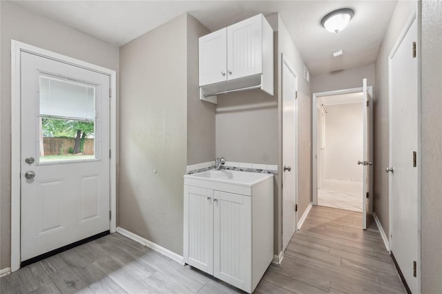 2417 NW 55th Ter, Oklahoma City, OK 73112 - clothes washing area with baseboards, a sink, and light wood finished floors