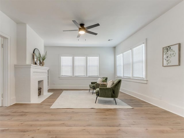 1132 NE 17th St, Oklahoma City, OK 73111 - sitting room featuring baseboards, ceiling fan, a fireplace, and light wood finished floors
