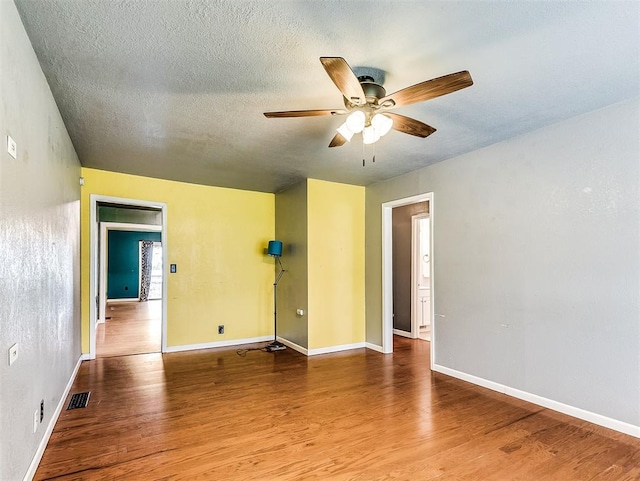 unfurnished room featuring a ceiling fan, baseboards, visible vents, and wood finished floors