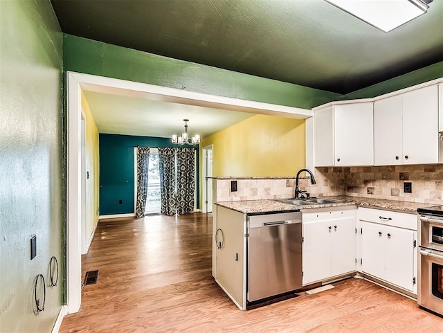kitchen featuring a sink, appliances with stainless steel finishes, a notable chandelier, and tasteful backsplash