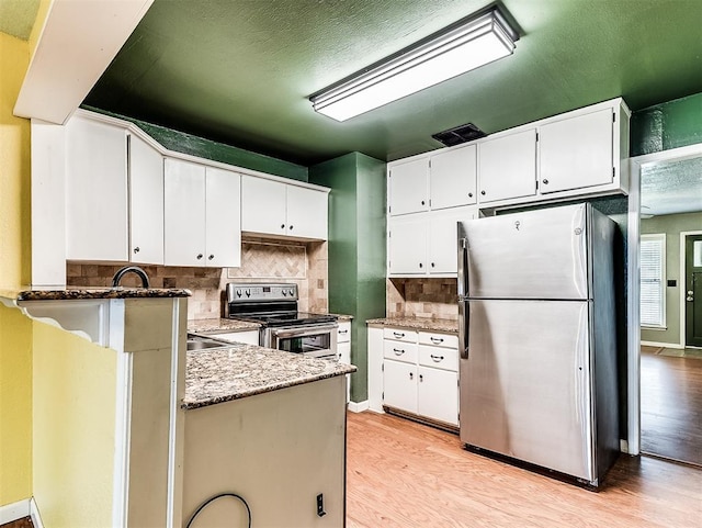 kitchen featuring backsplash, appliances with stainless steel finishes, light stone counters, white cabinets, and light wood-style flooring