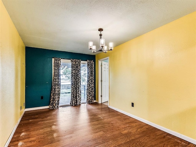 unfurnished room featuring baseboards, an inviting chandelier, and wood finished floors