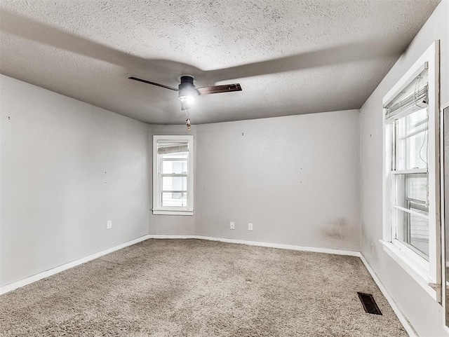 unfurnished room featuring a textured ceiling, ceiling fan, visible vents, and carpet