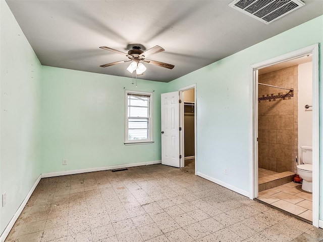 unfurnished bedroom featuring visible vents, baseboards, a walk in closet, and ensuite bath